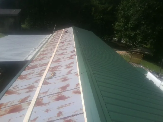 Old rusted panels beside newly installed green metal roofing — Wind Damage Roof Repair by Roofing Brothers in Westlake Village