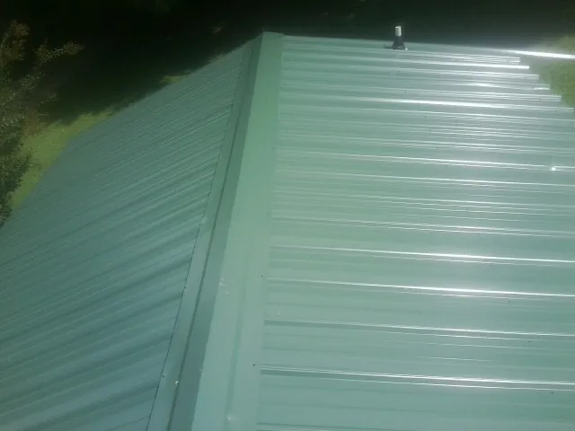 New green metal panels meeting at the ridge of a roof — Flat Roof Repair work by our crew in Westlake Village