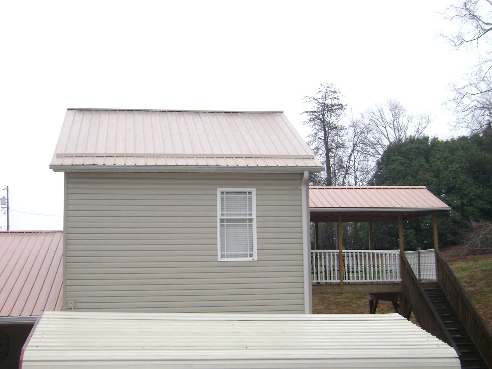 Tan metal roofs on a two story addition and attached porch, from a Roof Replacement job in Westlake Village