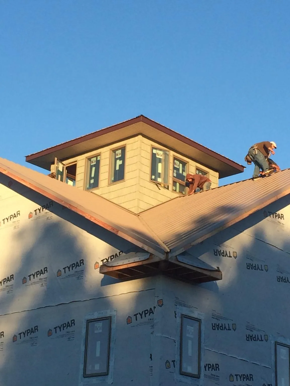 Roofers working around a rooftop cupola on a new metal roof at sunset — Roof Waterproofing in Westlake Village by Roofing Brothers